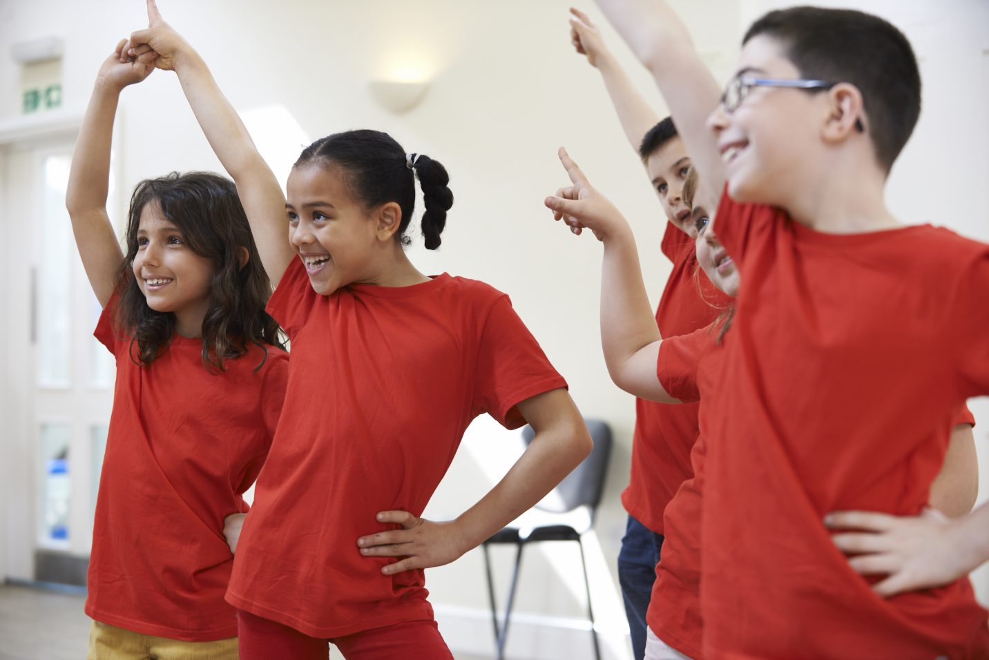 Kids in red shirts smiling and dancing
