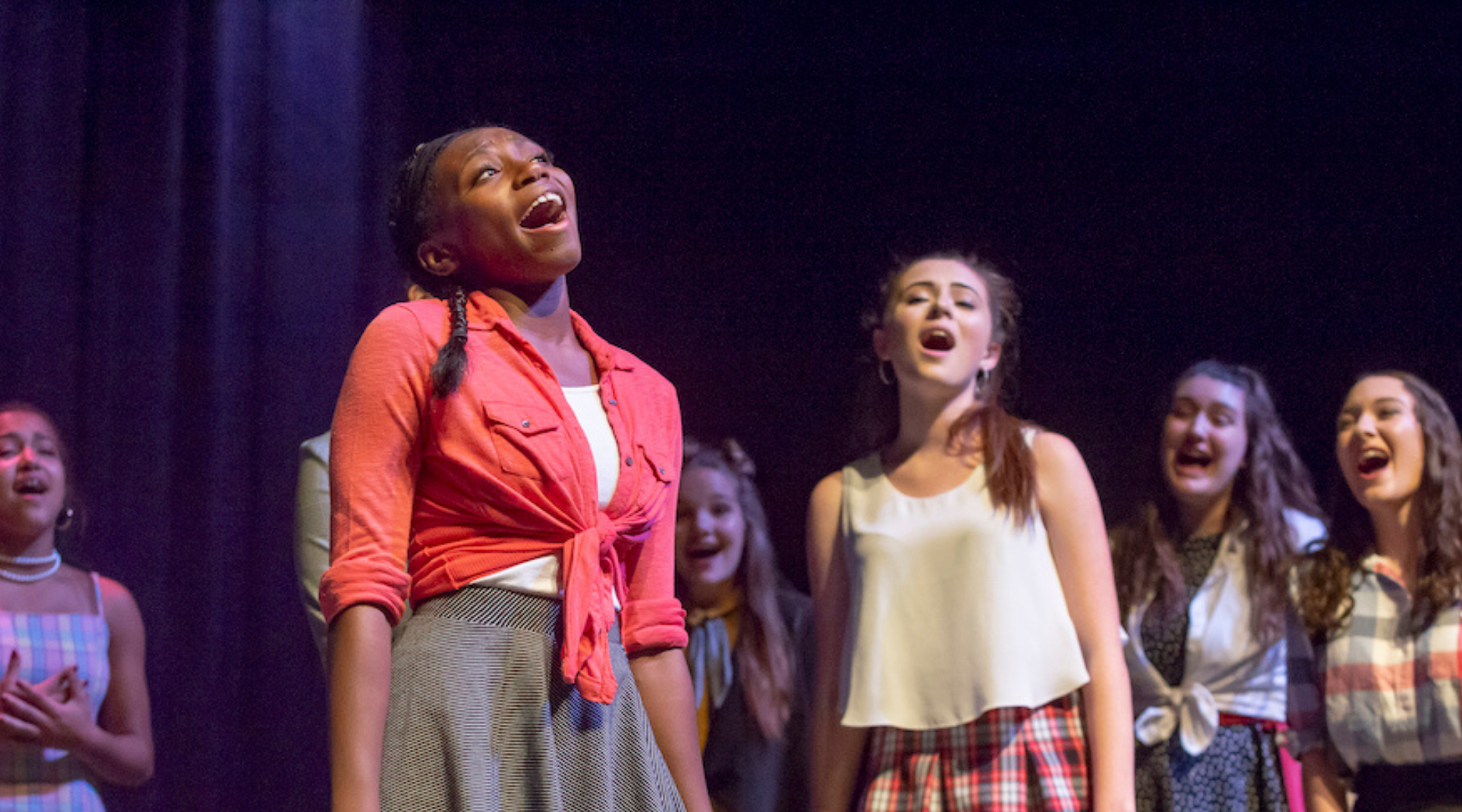 teen in red shirt singing with kids in the background