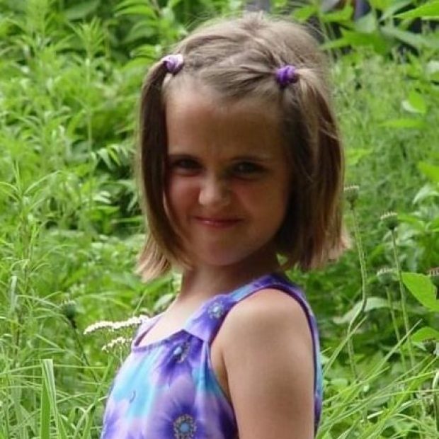 Young girl with purple flower shirt and hair ties smiling