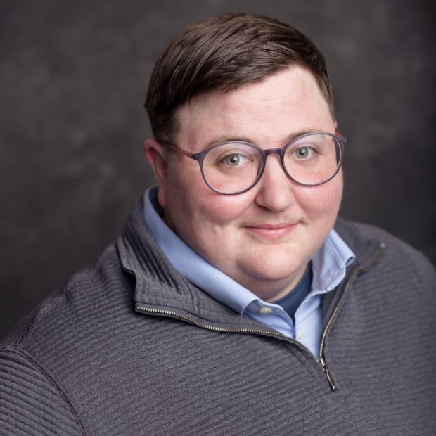 Person with glasses and grey quarter zip