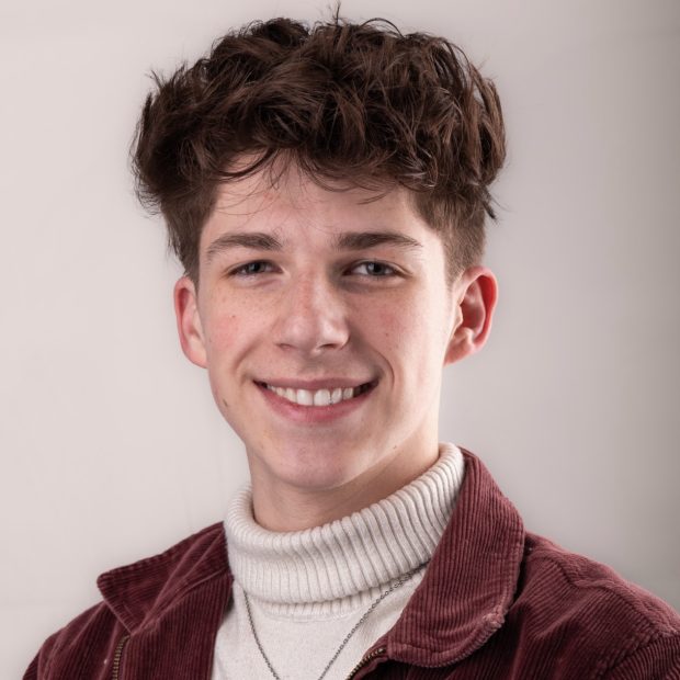 Young man with turtleneck sweater and maroon jacket smiling
