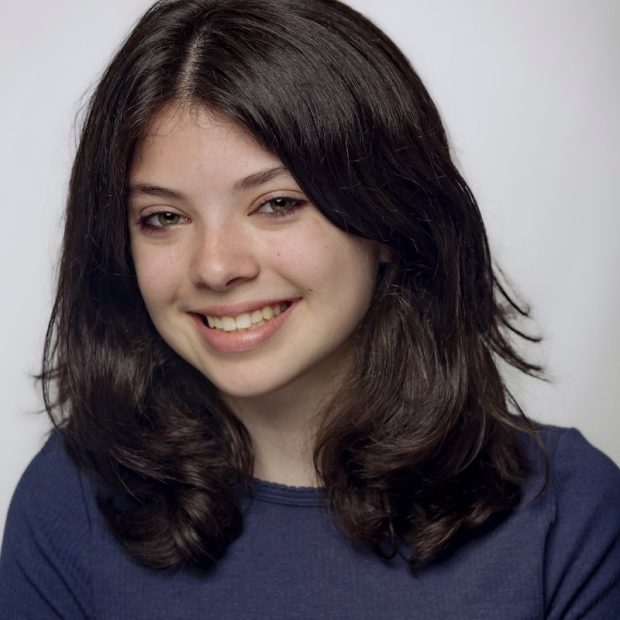 Teen girl with black hair and a blue shirt with a light grey background