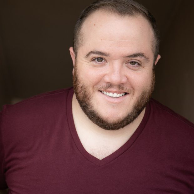 Man with a beard with maroon shirt and brown background