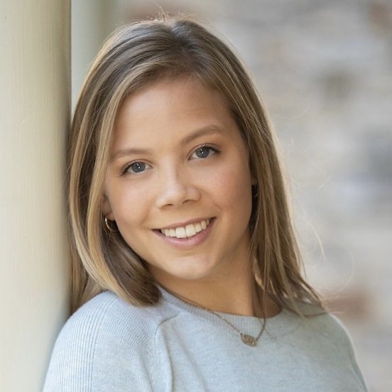 Young woman with blonde hair and blue eyes with a light blue sweater and a neutral background