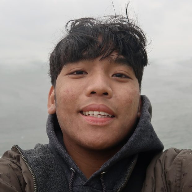 Young man with black hair and a hoodie with a neutral background