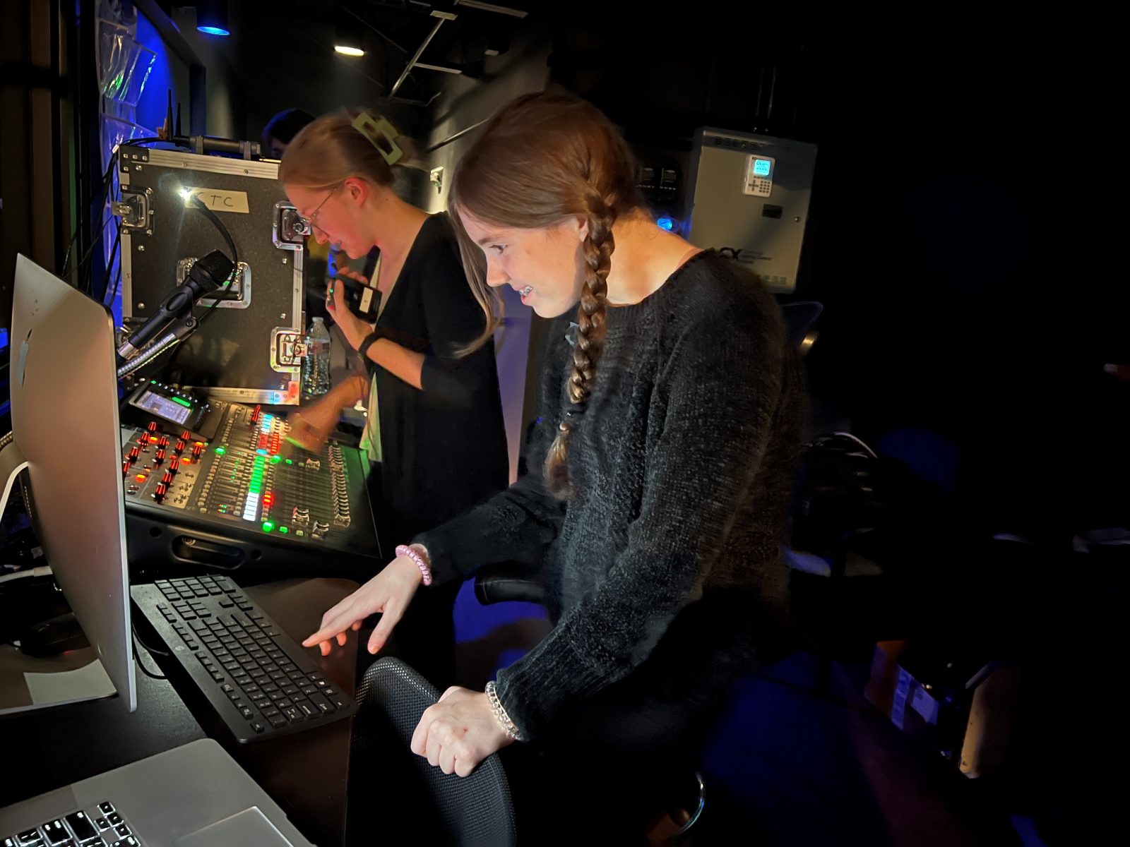 Two teenagers working light board backstage